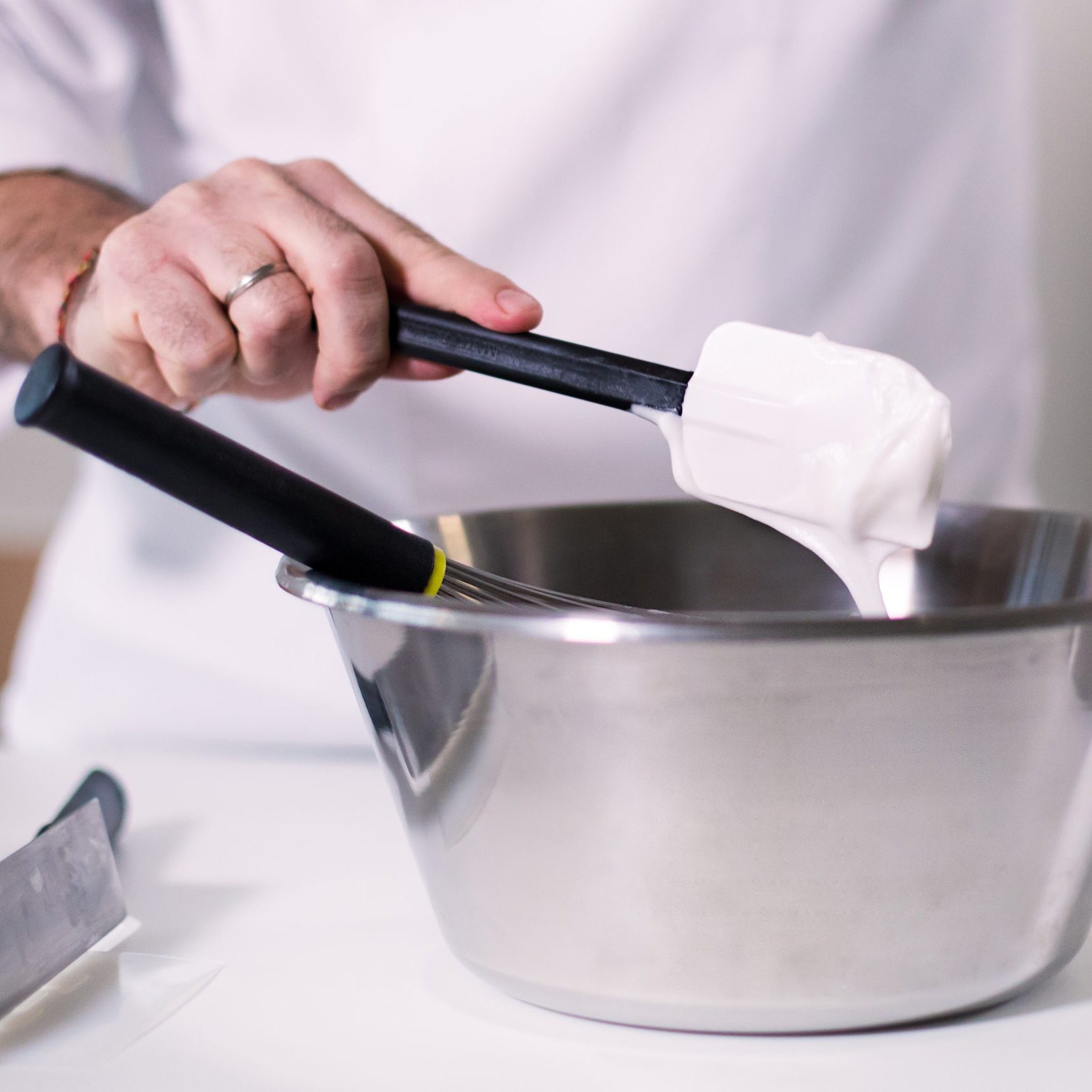 Person holding a Matfer spatula with white cream over a metal bowl