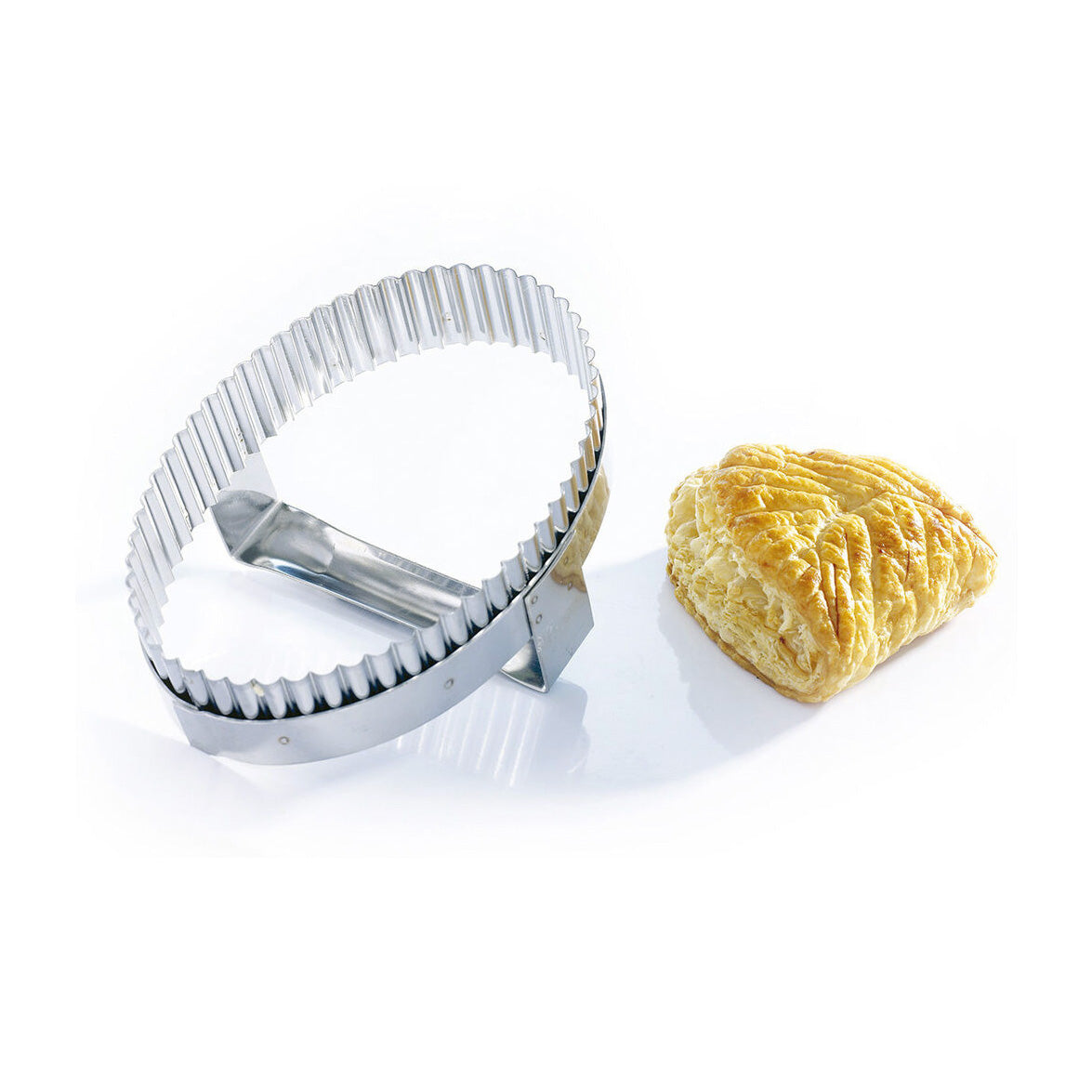 Metal cutter next to a turnover on a white background