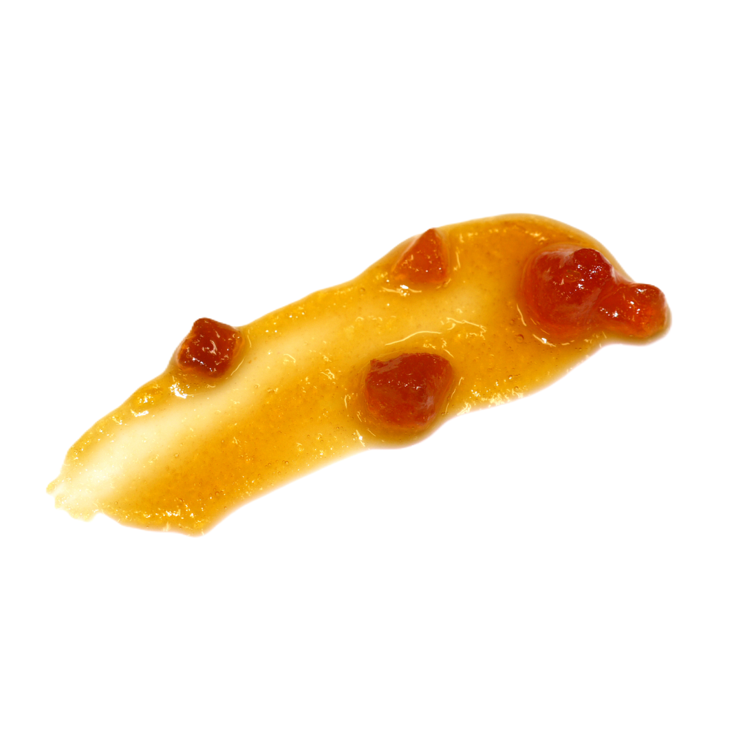 A smear of golden orange-yellow MEC3 peach flavouring spread, containing small red fruit pieces, isolated on a solid white background.