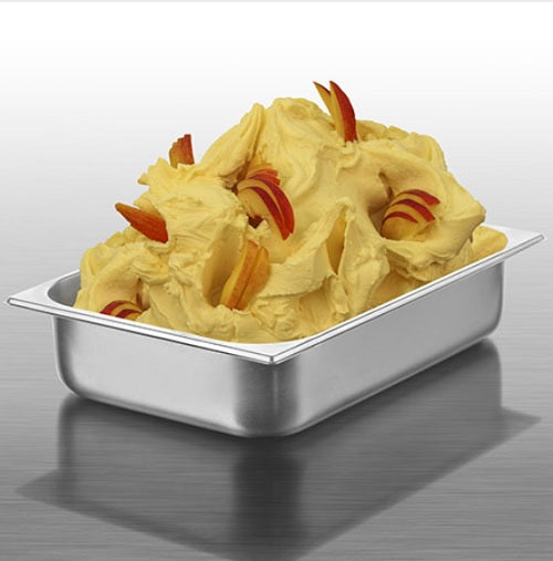 A stainless steel food pan filled with pale yellow gelato, garnished with red-orange fruit slices, on a reflective gray surface.