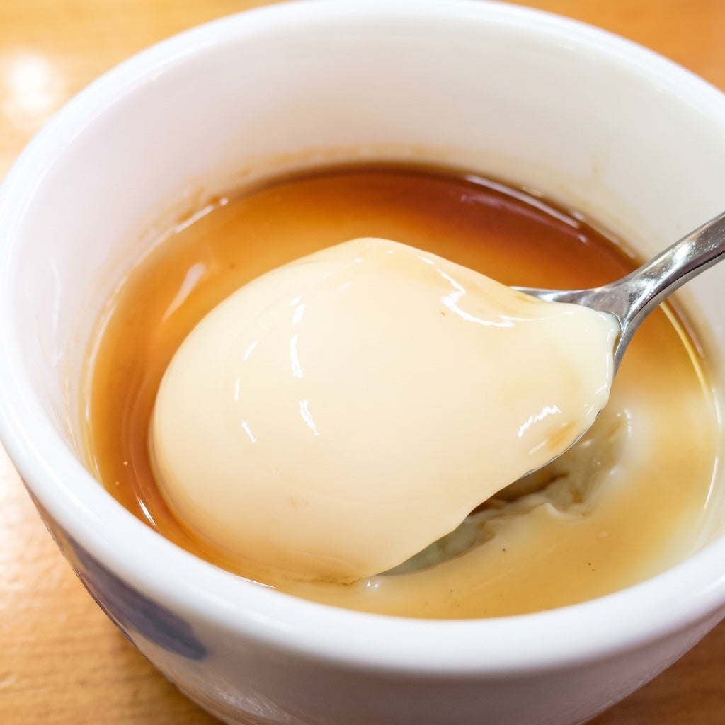 Spoonful of dessert over a bowl of custard on a wooden surface