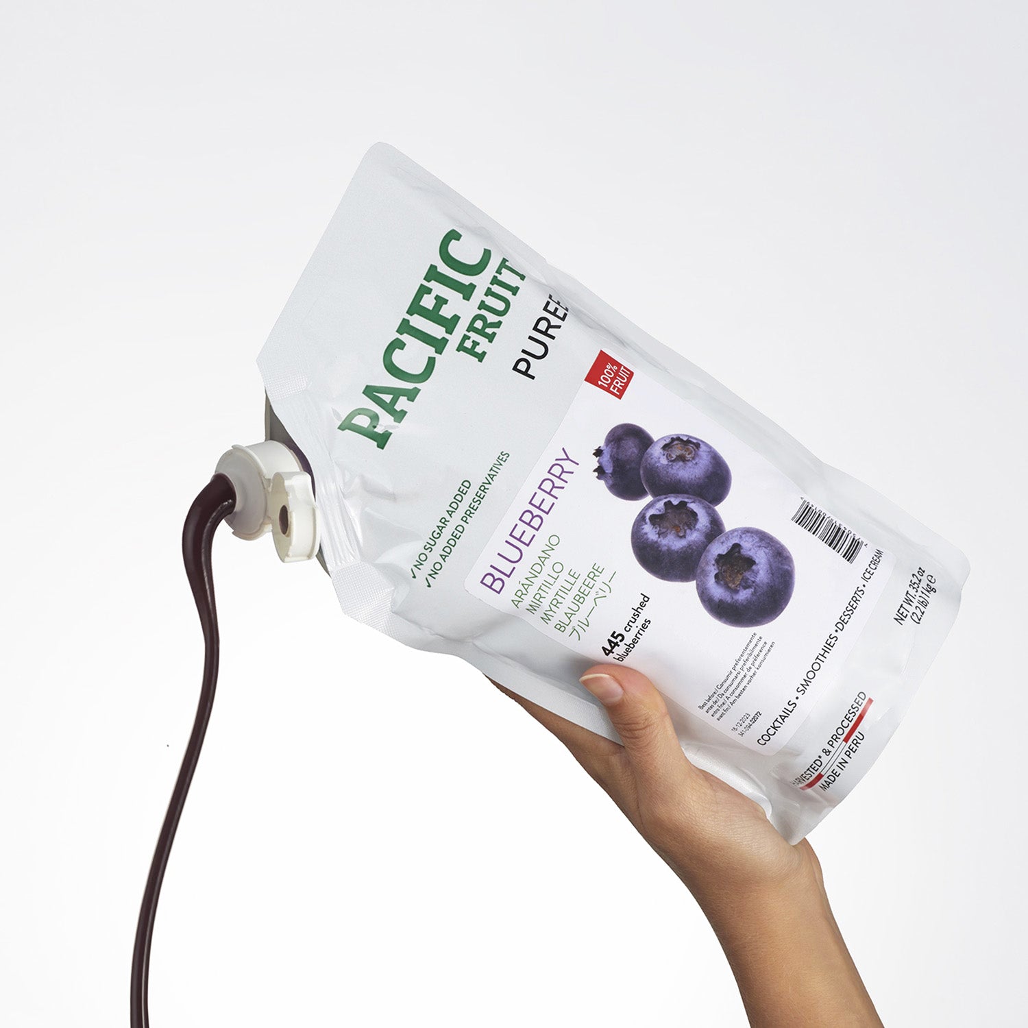 Hand holding a Pacific Fruit Puree Blueberry package with a white background