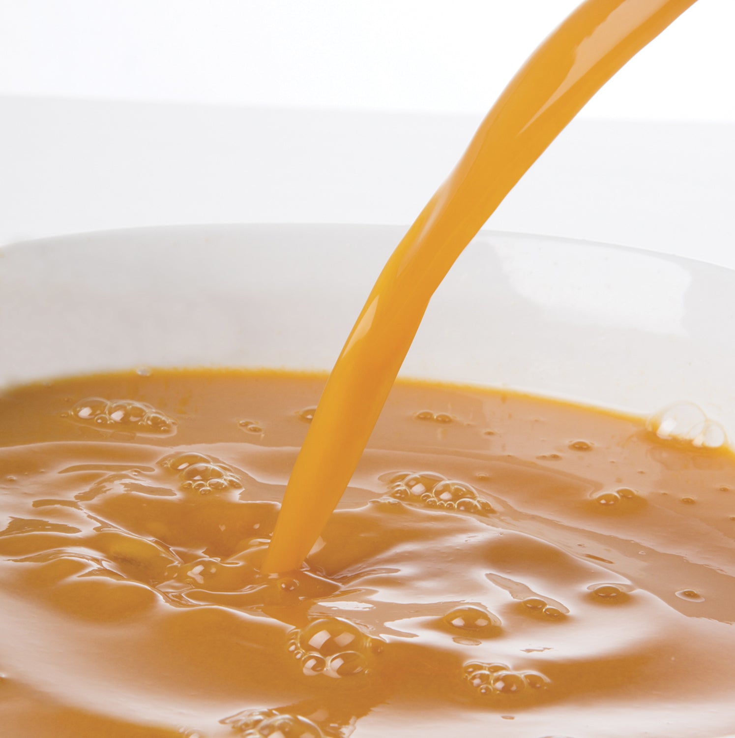 Pacific Fruit Golden Berry puree being poured into a white bowl on a light background