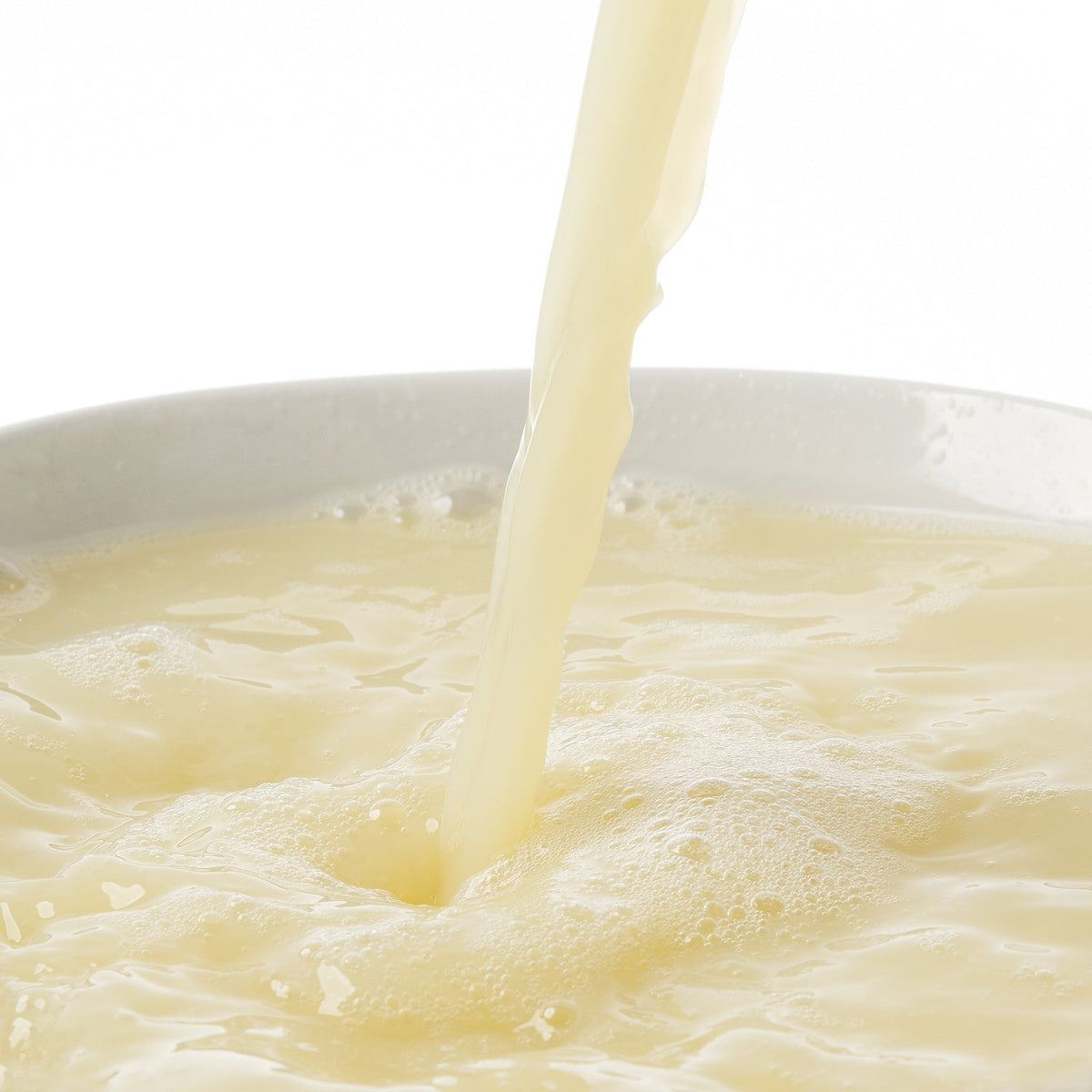 White bowl with lemon puree being poured into it on a white background