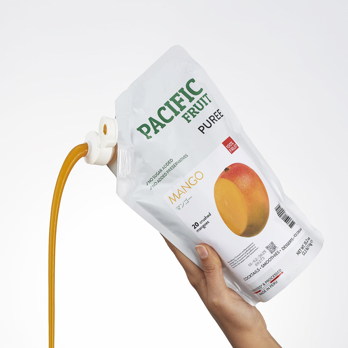 Hand holding a pouch of Pacific Fruit Puree Mango on a white background