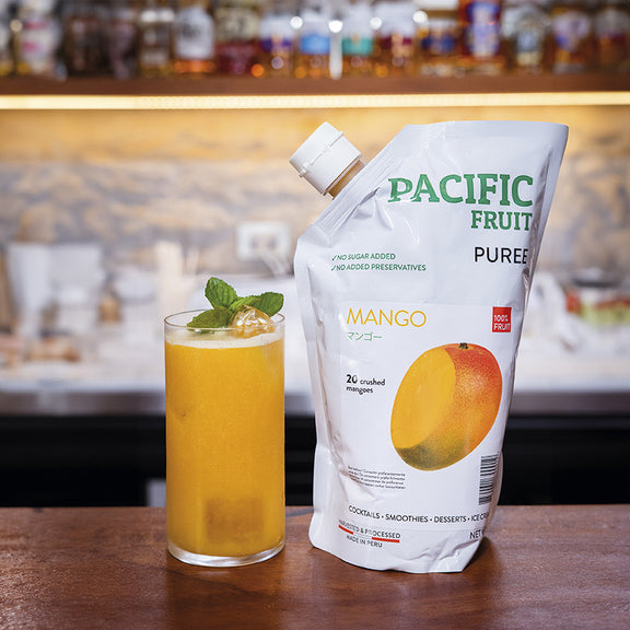 Mango cocktail in a glass with a mango puree pouch on a bar counter