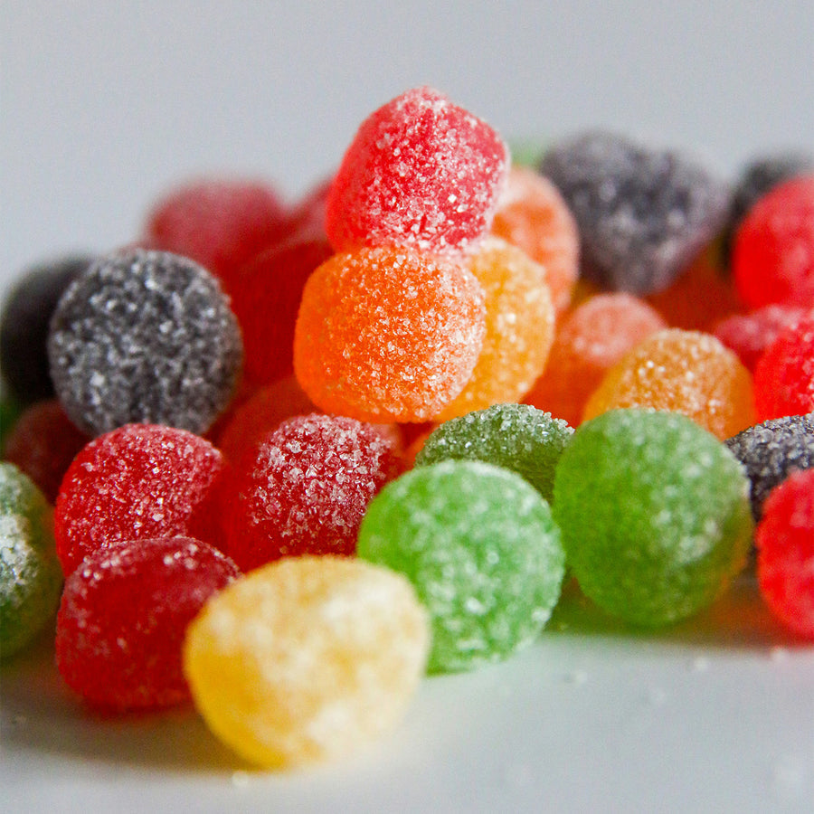 Orange flavoured gummy candies made with Pacific Fruit orange shelf stable puree on a white surface