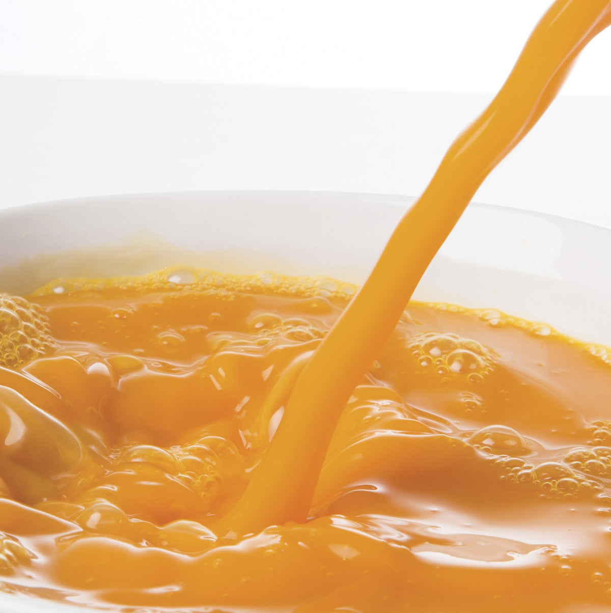 Passion Fruit puree / juice being poured into a bowl with a white background