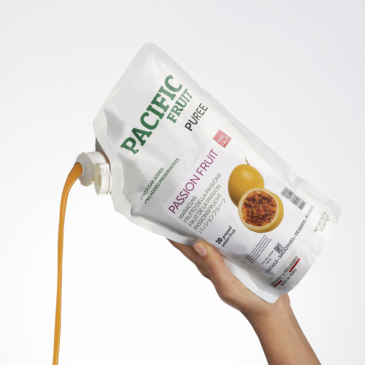 Hand holding a bag of Pacific Fruit Passion Fruit Puree with a white background