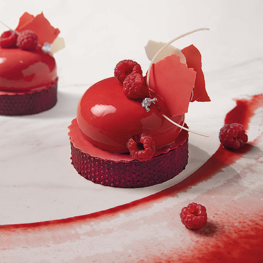 Red dessert made with Pacific Fruit raspberry shelf stable puree with raspberry toppings on a white background