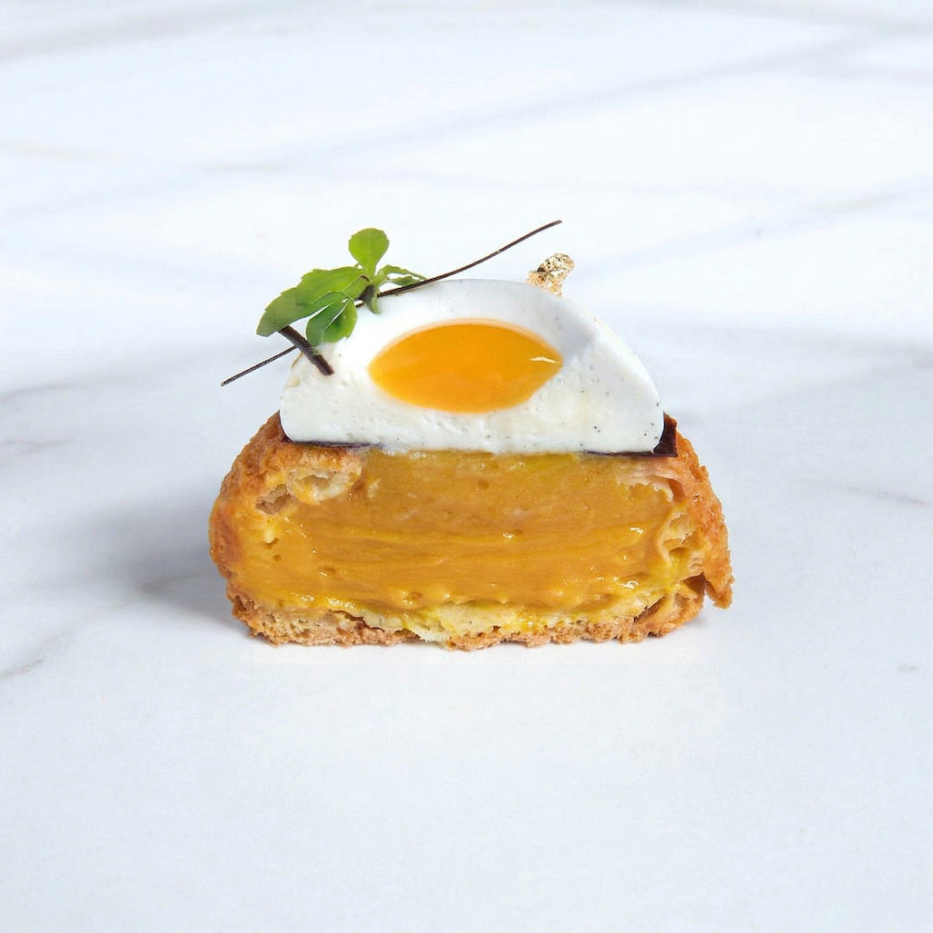 Dessert with pastry filling made using Pacific Fruit shelf stable turmeric puree on top against a white background
