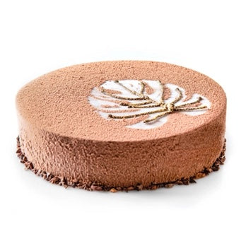 A round chocolate cake with a textured brown frosting, decorated with a white leaf pattern and gold drizzle on top, set against a plain white background.