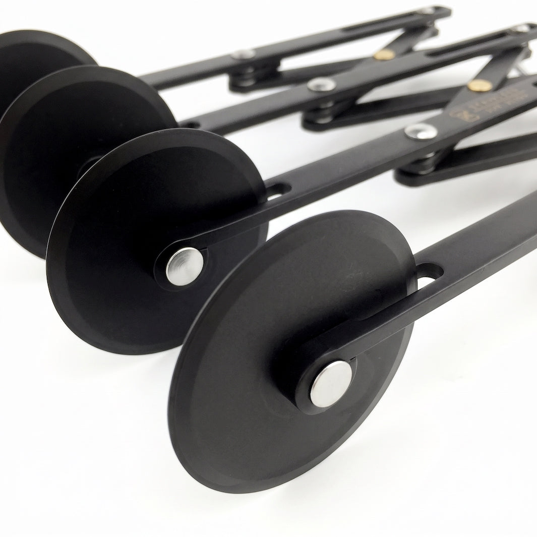Four black dough cutter wheels shown diagonally on a clean white background.