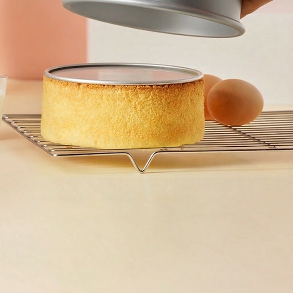 Round cake being removed from Sanneng Anodized Deep Round Cake Pan with removable bottom on a cooling rack.