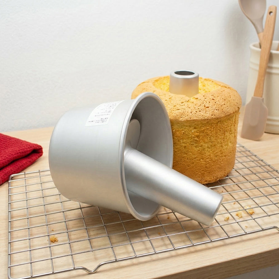 Silver Sanneng angel and chiffon cake pan with a yellow cake on a cooling rack