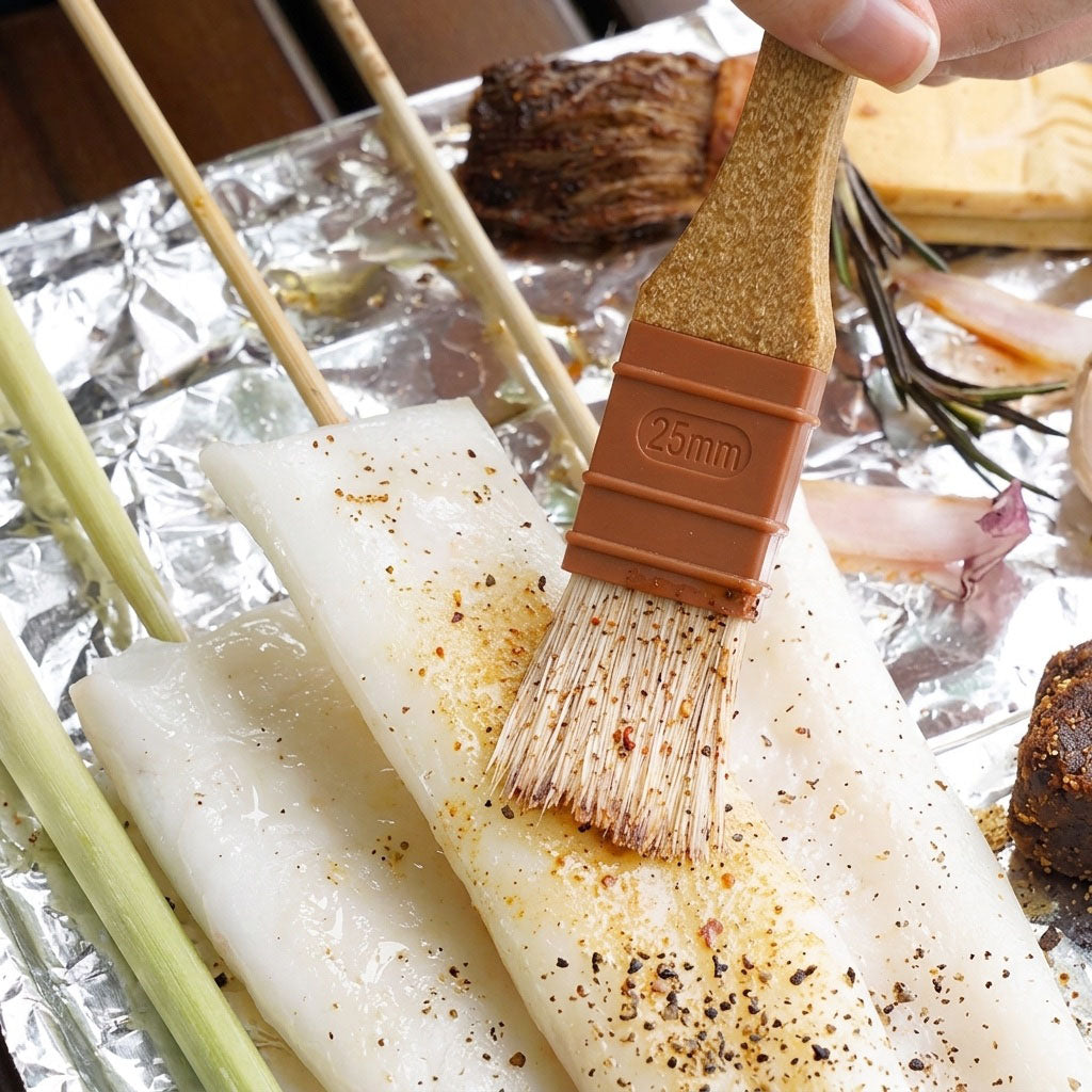 Coated skewers with a Sanneng eco handle brush on a foil-covered surface