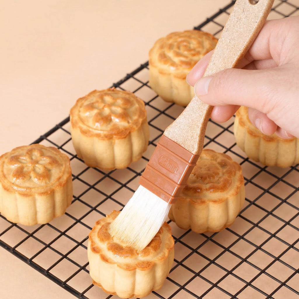 Person brushing a small baked good with a Sanneng eco handle pastry brush on a cooling rack.