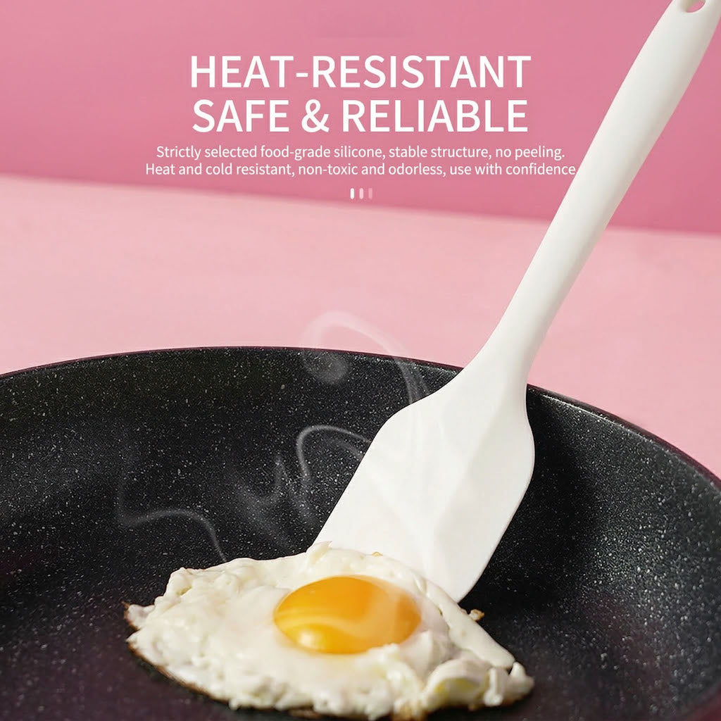 Sanneng white heat-resistant silicone spatula lifting a fried egg from a black pan on a pink background