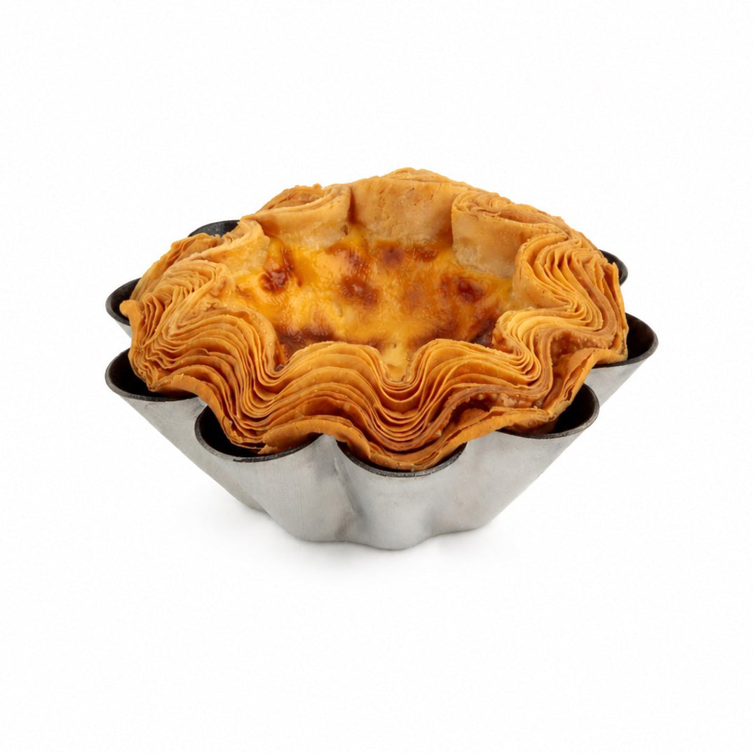 A baked pastry tart with a flaky, layered golden-brown crust in a scalloped metal pie tin, isolated on a white background.
