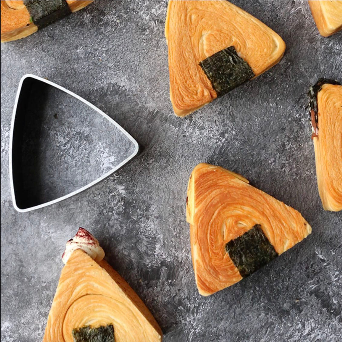Triangular pastry slices with a dark filling on a gray surface