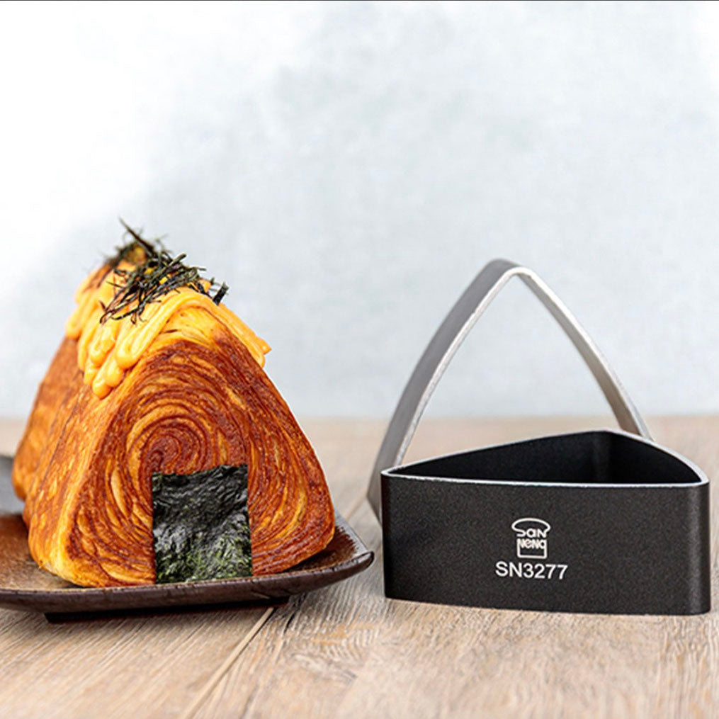 Croissant bread with seaweed on a plate next to a black non-stick bread ring mold with 'Sanneng' branding.