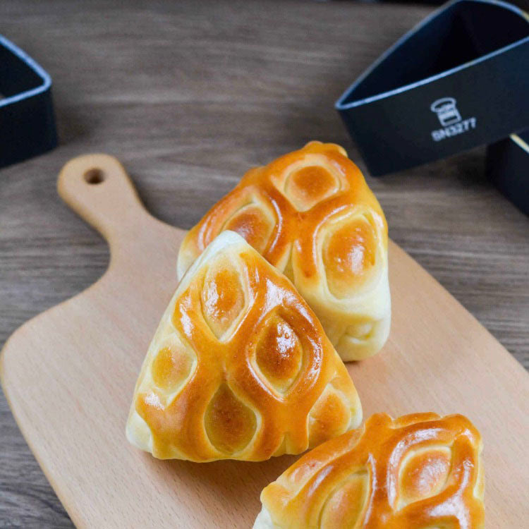 Three triangular bread rolls on a wooden cutting board with a branded Sanneng ring mould in the background.