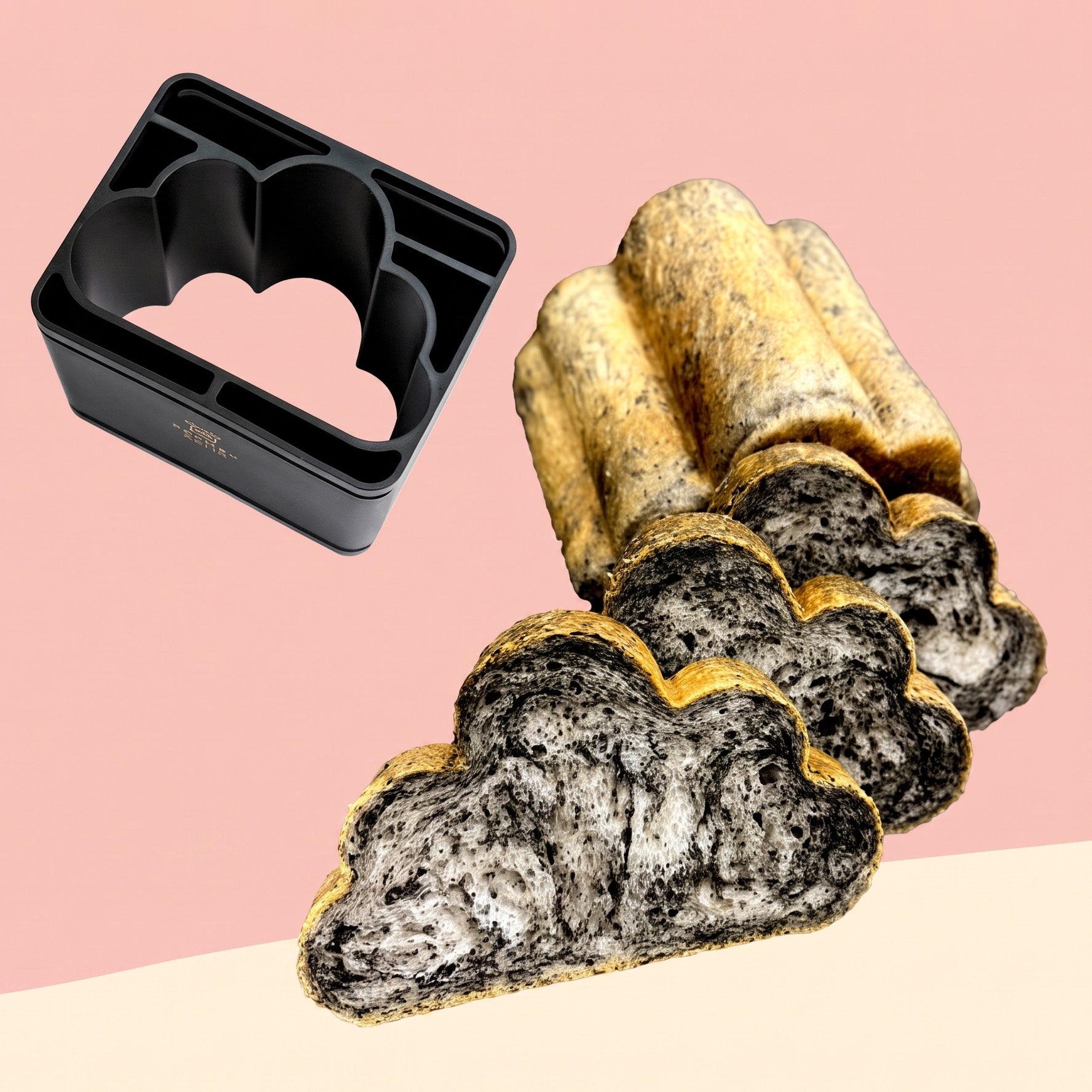 Cloud-shaped black sesame bread with a golden-brown crust, shown sliced to reveal a marbled black and white crumb, alongside Sanneng black baking mold on a pink and cream background.