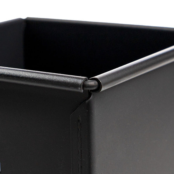 Close-up of a matte black metal Sanneng shokupan pan corner, showing the reinforced rim and interior edge against a white background.