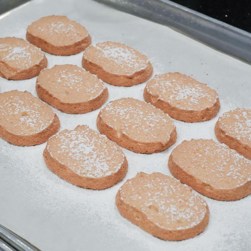 Baked dacquoise cookies using Sanneng Acrylic Template on a baking tray with powdered sugar on top