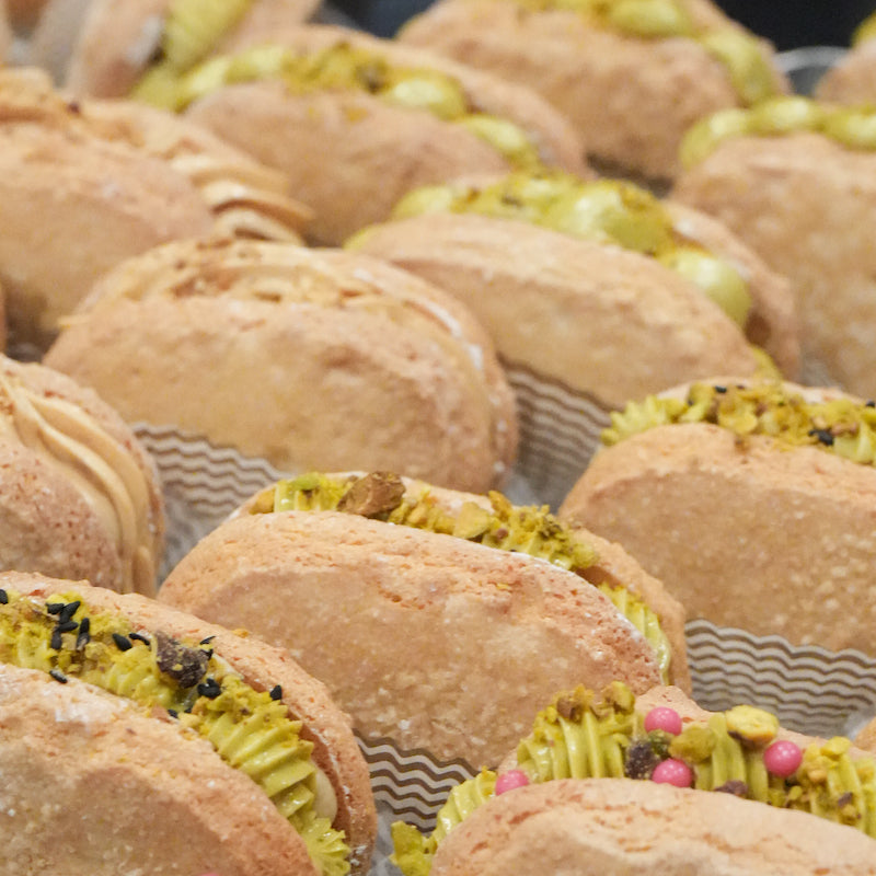 Close-up of dacquoise pastries with green pistachio filling and decorative elements