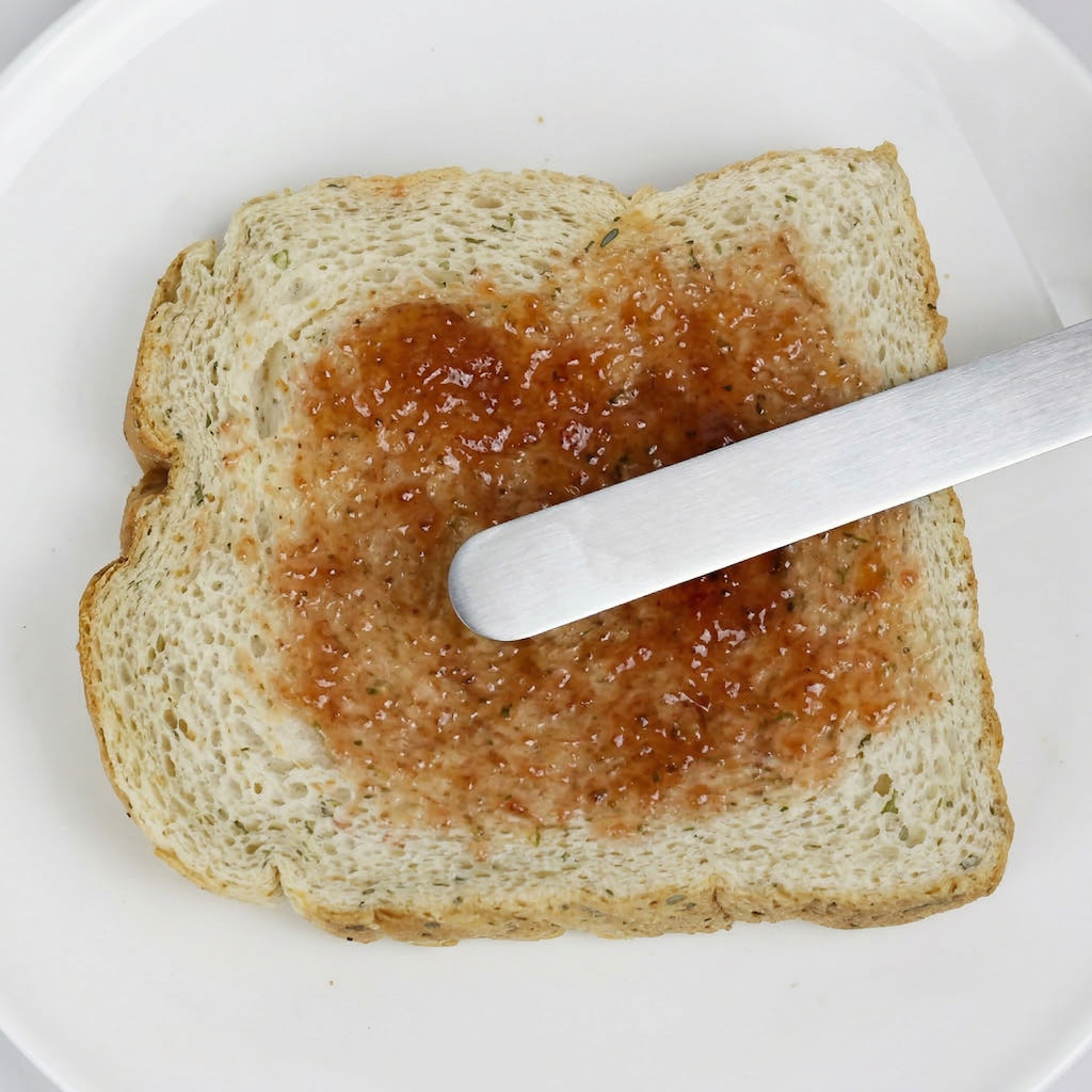 Slice of bread with jelly and the Sanneng cake remover on a white plate
