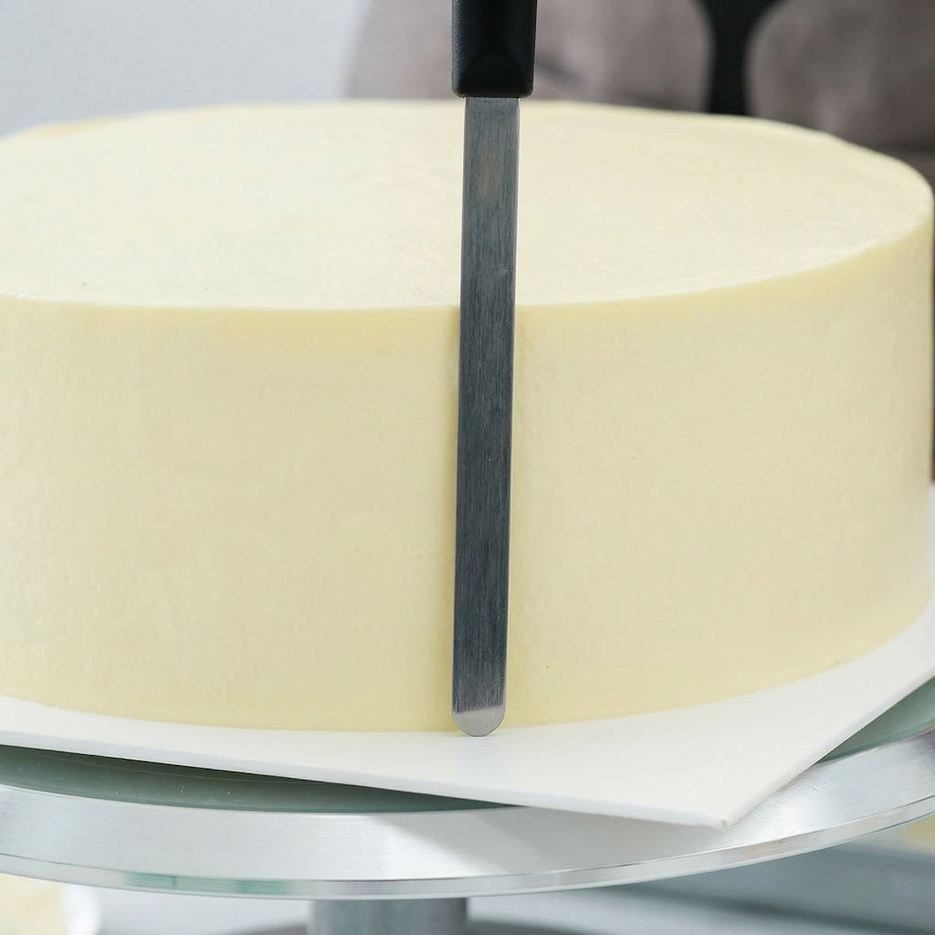 Close-up of a Sanneng stainless steel cake remover tool against the side of a cake