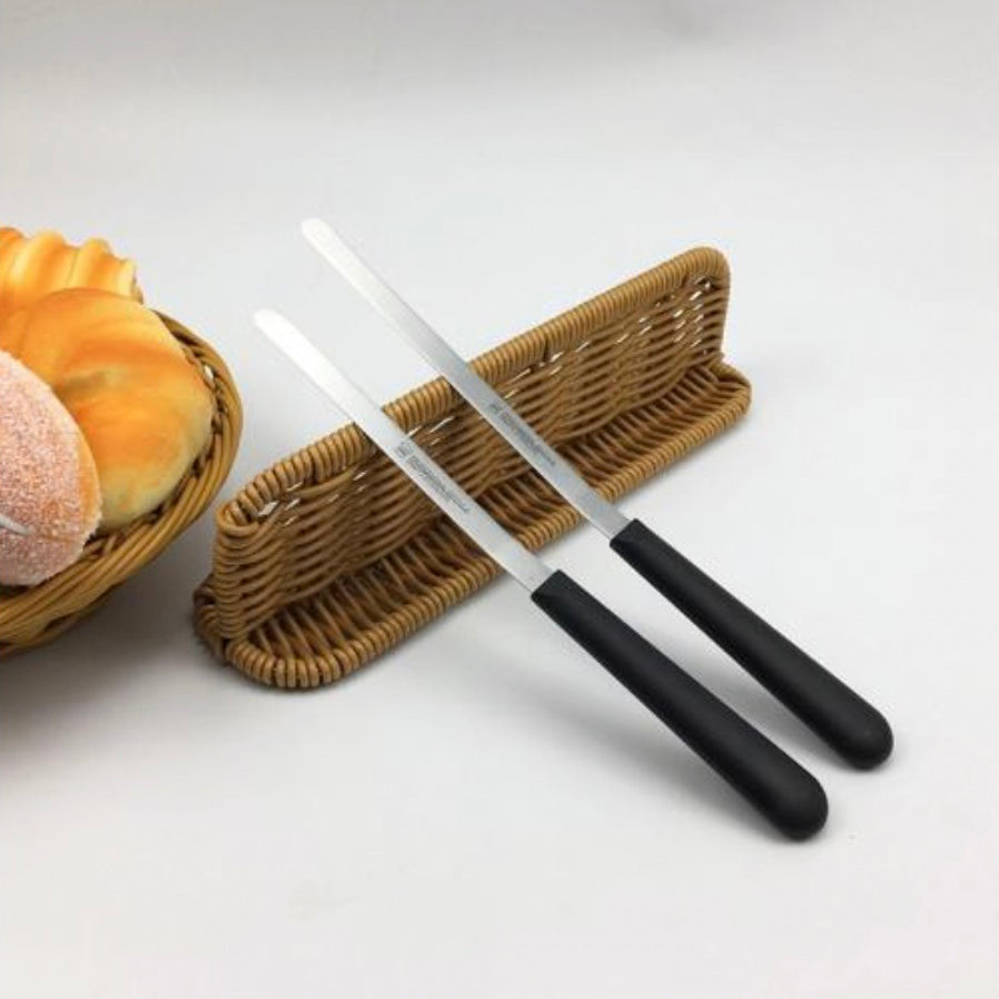 Two Sanneng stainless steel cake remover tools with black handles on a white surface next to a woven basket with bread.