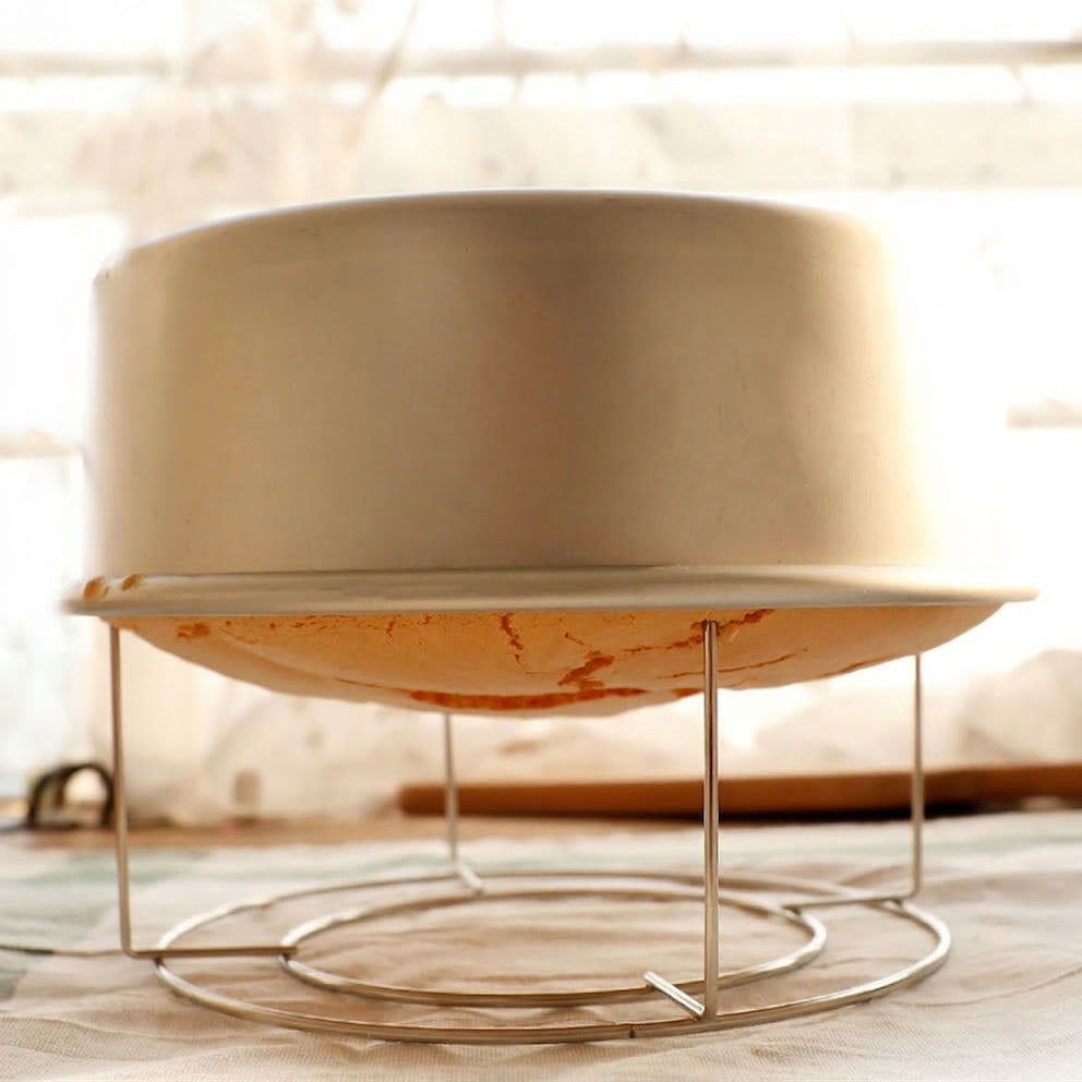 Sanneng stainless steel inverted cake cooling stand on a wooden surface with a blurred background