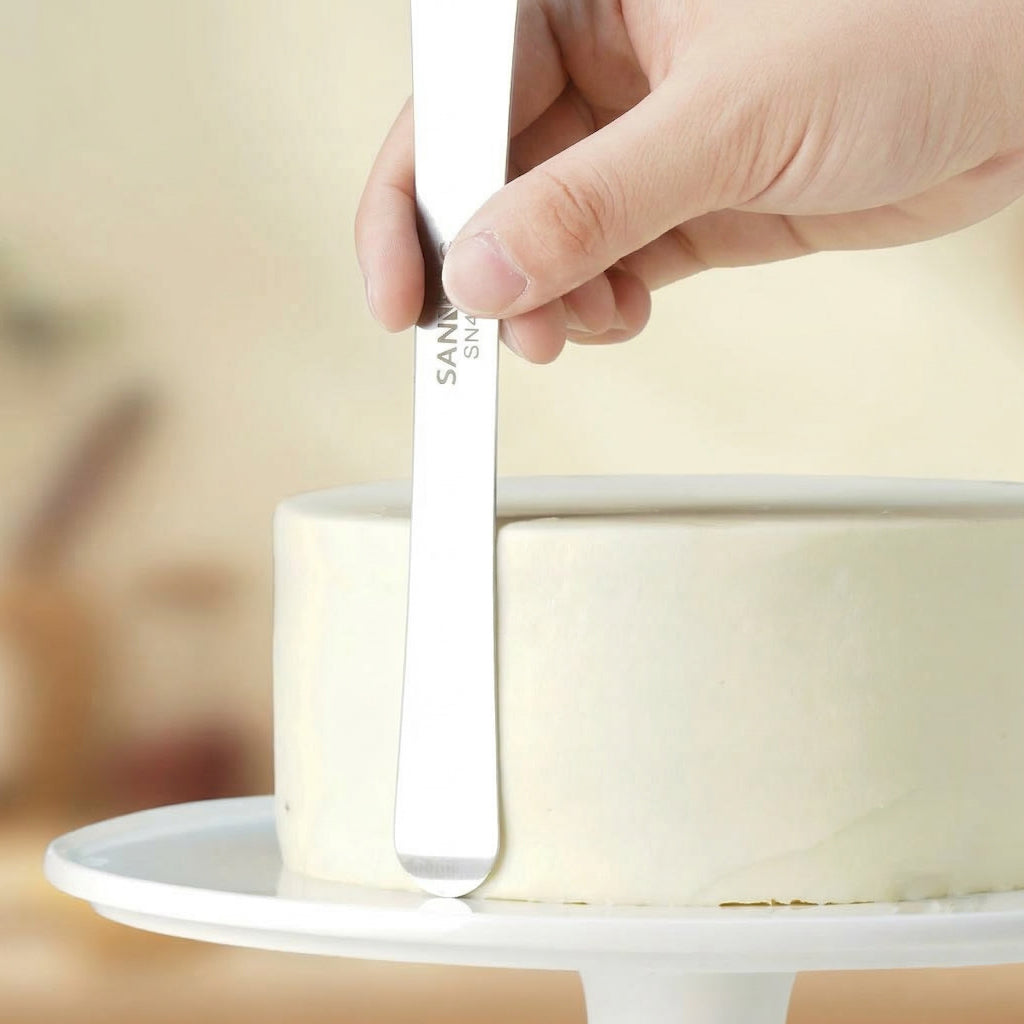 Hand holding a SN4061 multi-purpose stainless steel spatula with 'Sanneng' branding on a blurred background