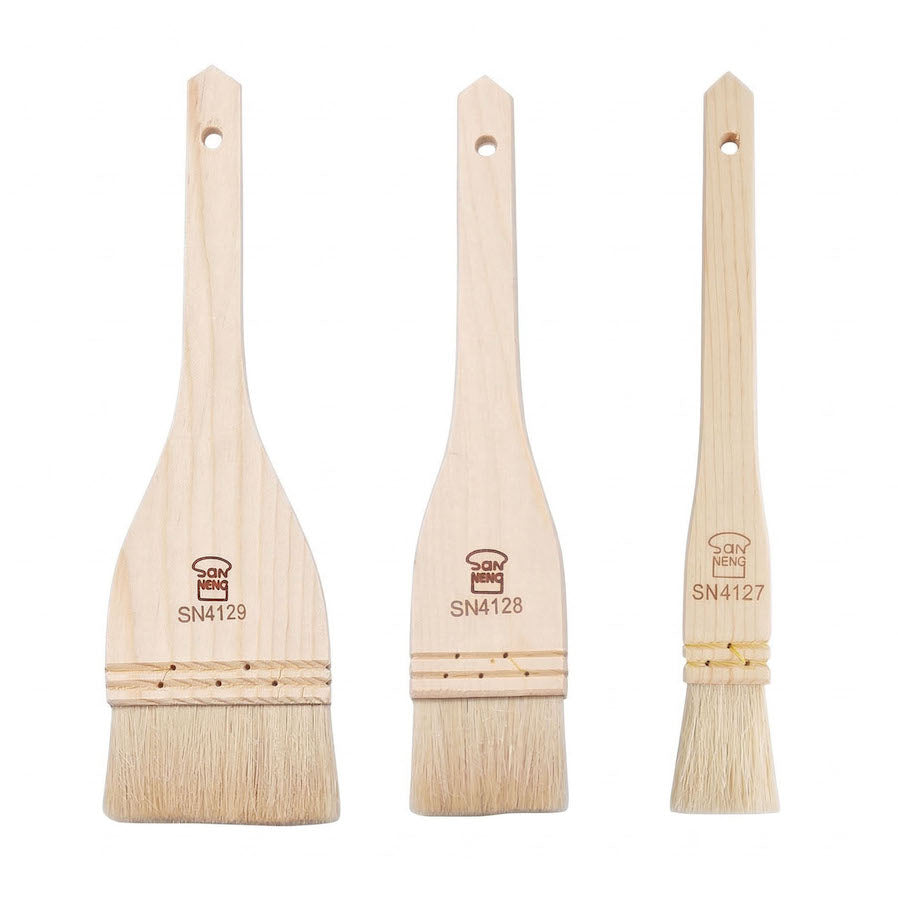 Three wooden Sanneng pastry brushes with bristle heads on a white background