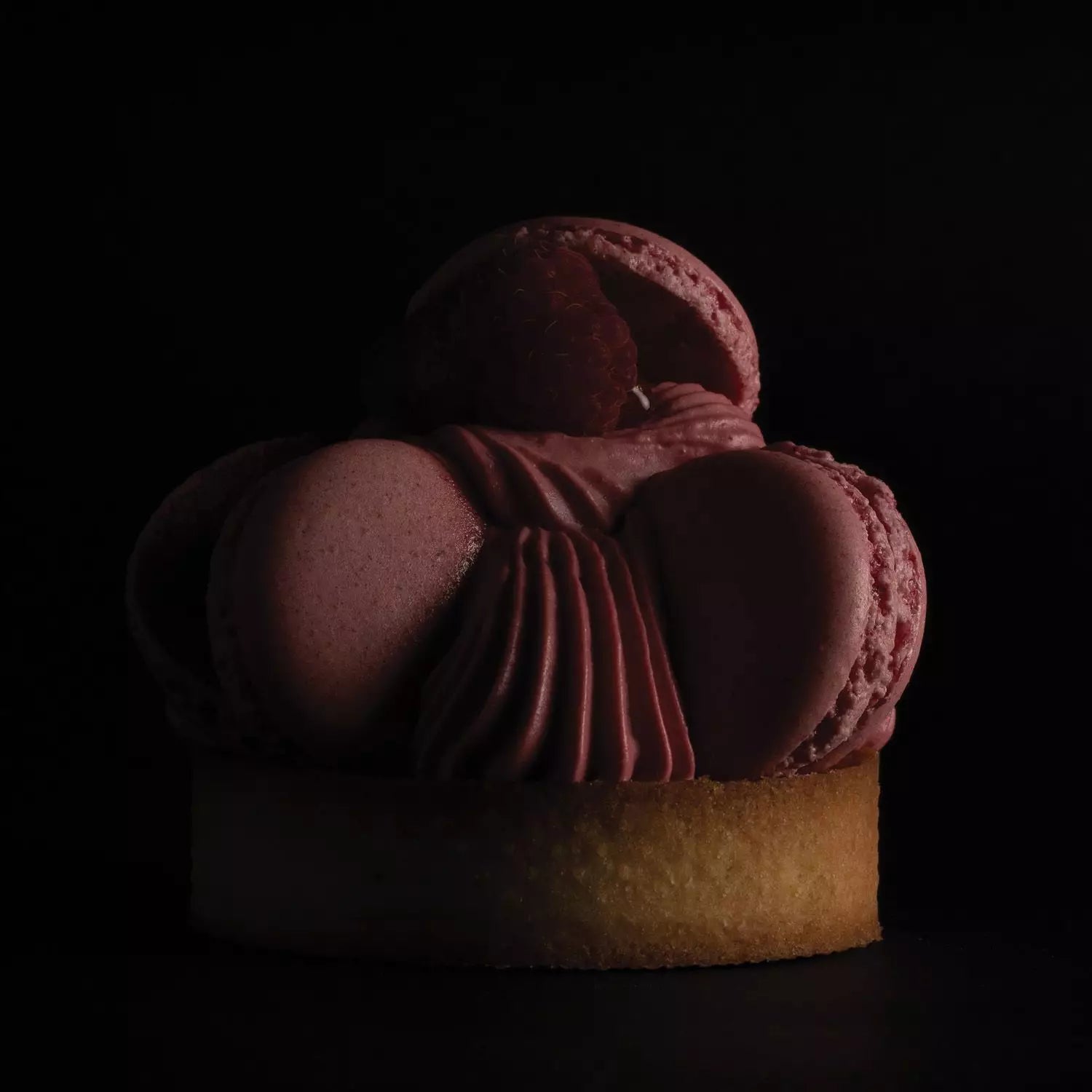 Cupcake with pink macaron topping on a black background