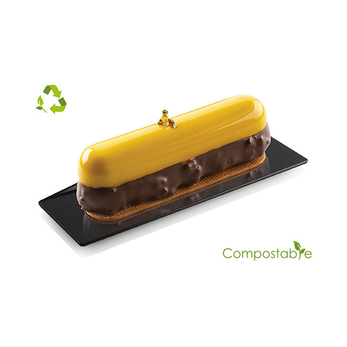 Chocolate eclair with a yellow top on a black plate, featuring a compostable logo.