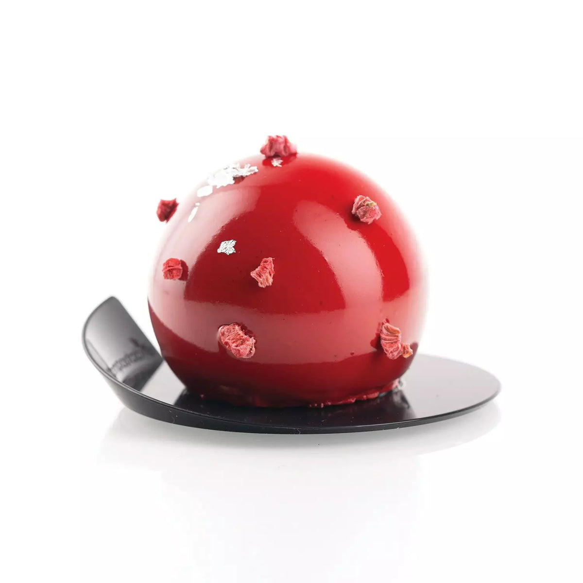 Red dome-shaped dessert with floral decorations on a black plate against a white background