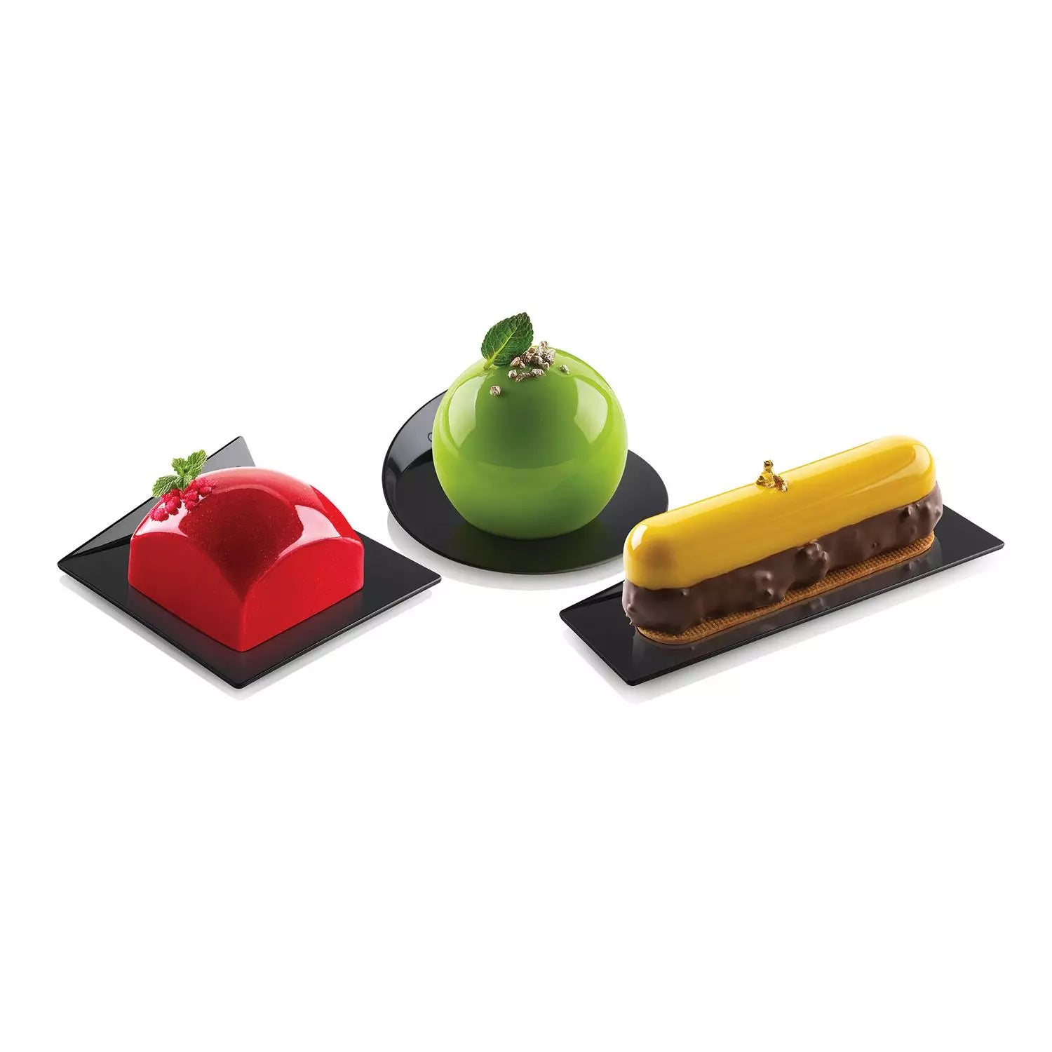 Three colorful desserts on black square plates against a white background