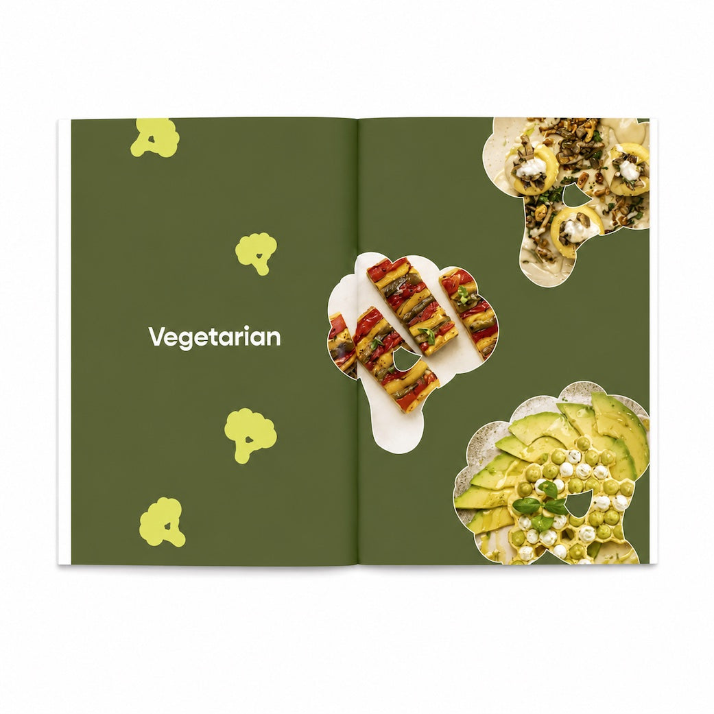 An open Silikomart recipe book with a dark olive green cover design, the word 'Vegetarian' printed on the left page, and several food photos arranged in irregular cutout shapes on the right page.