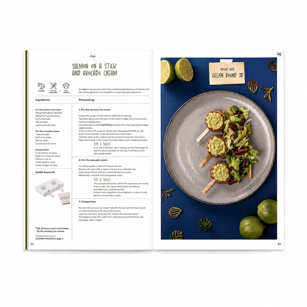 An open Silikomart recipe book showing a recipe for salmon on a stick and avocado cream. The left page contains ingredients, prep time, cook time, and step-by-step directions in a clean serif font.