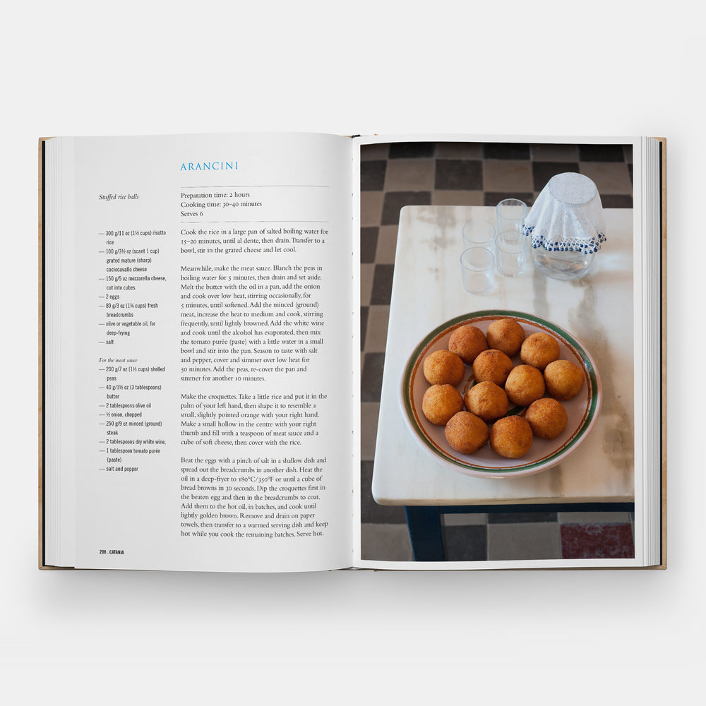 Open book showing a recipe for arancini with a photograph of a dish on a table.