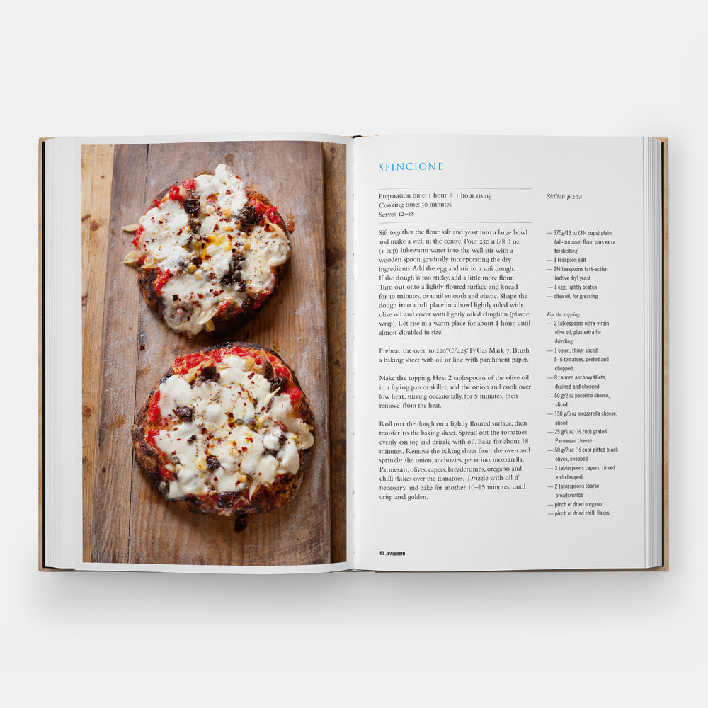 Open cookbook showing a recipe with two bagels topped with cream cheese and toppings on a wooden board.