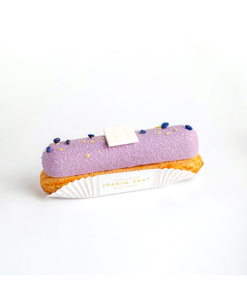 Purple eclair with gold sprinkles on a white background