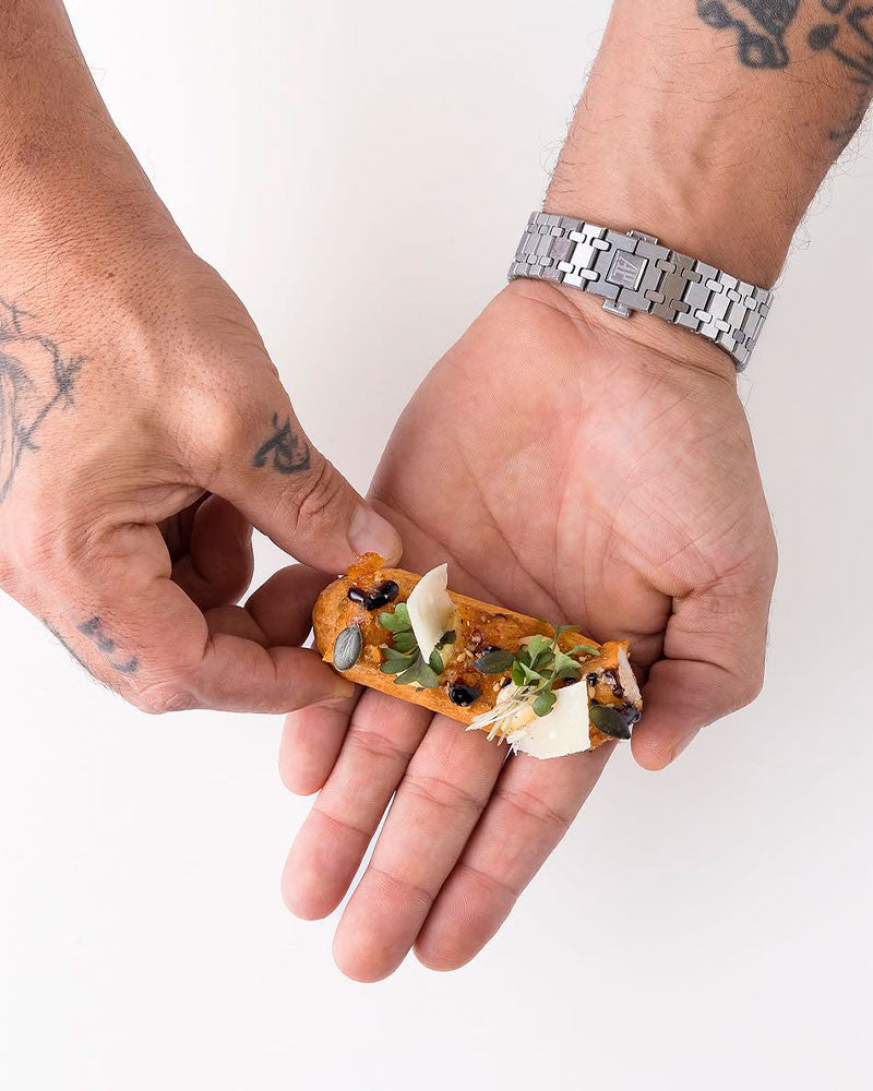 Joakim holding a small eclair with a white background