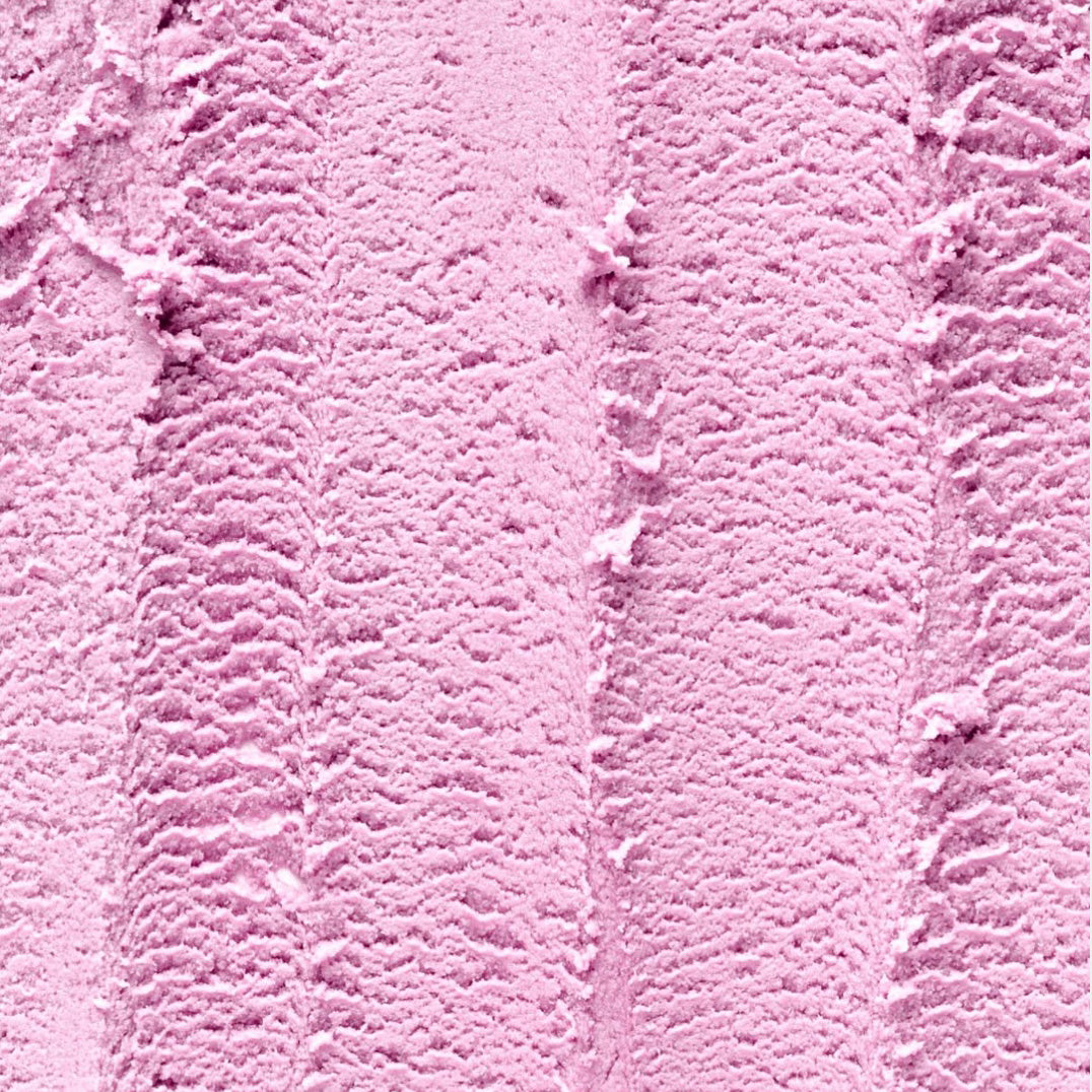 A close-up texture shot of light pink ice cream with visible swirls and soft peaks.
