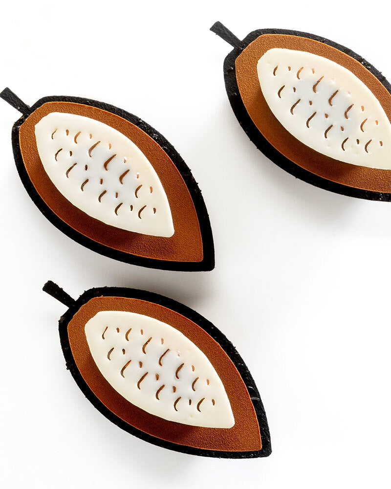 Three wooden leaf-shaped pastries with cut-out patterns on a white background