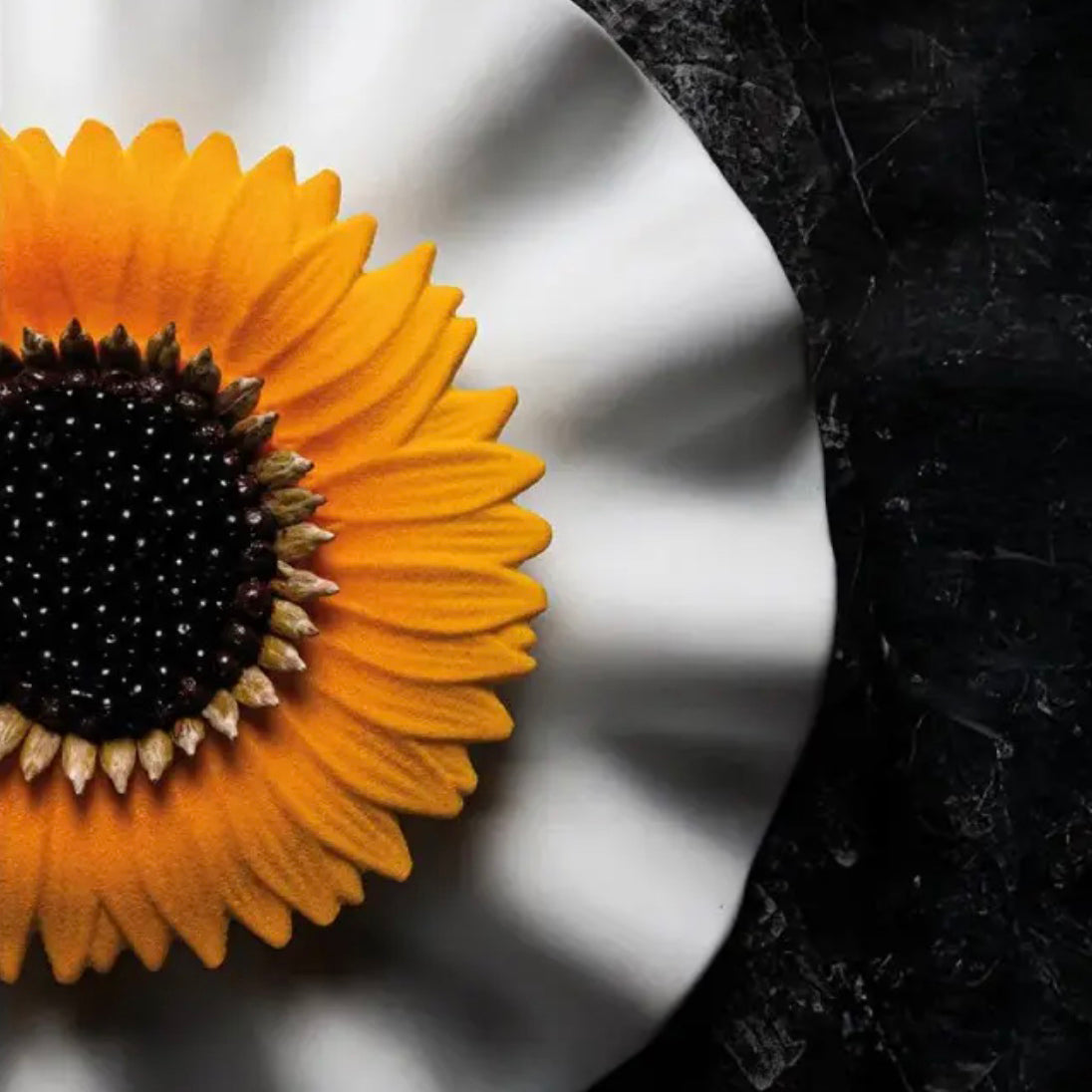 Sunflower plated dessert on a white plate with a dark background