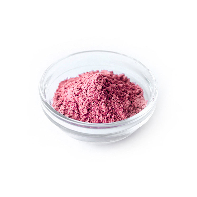 Clear glass bowl filled with pink Sol Fresh strawberry freeze dried powder on a white background